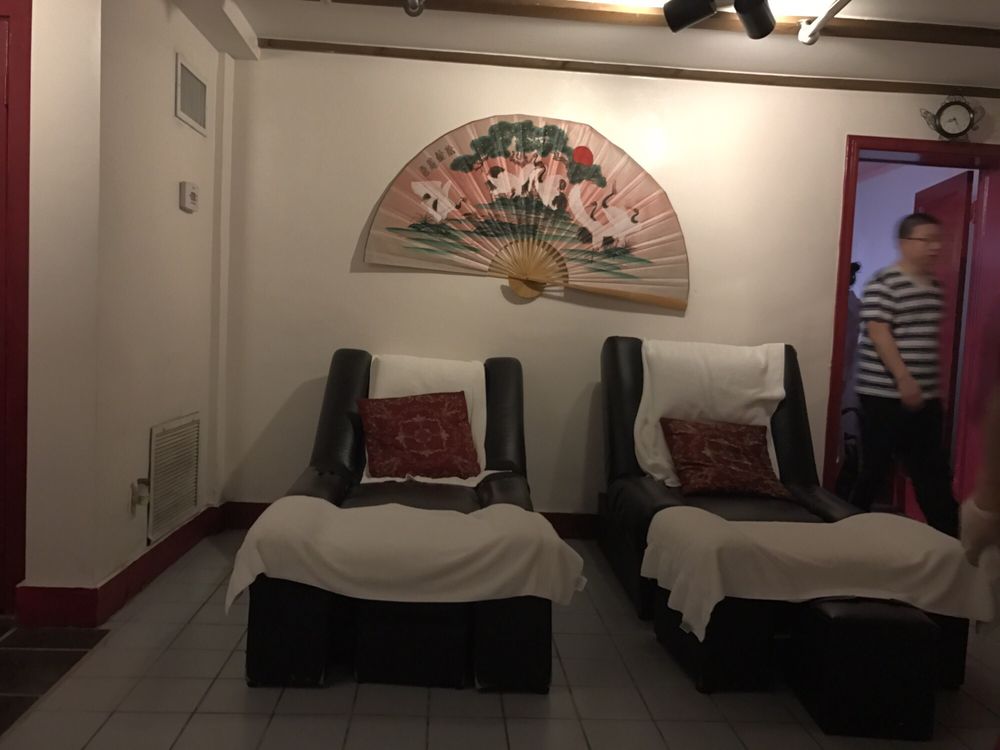 Two black reclining chairs with white towels and a painted crane fan on the wall