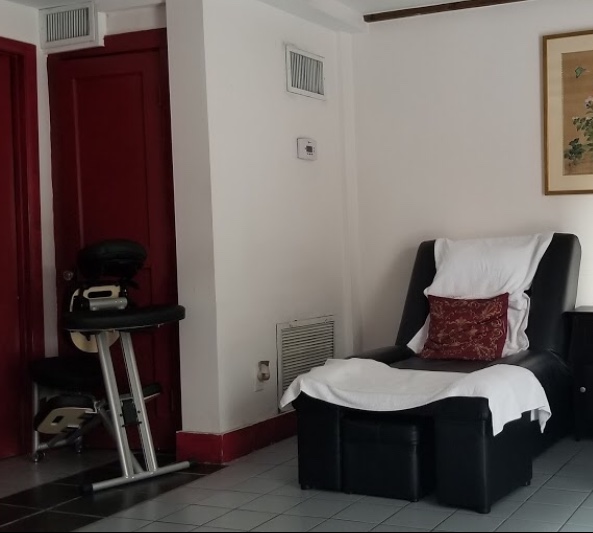 A black reclining chair with a red pillow, white towels, and a deep red door