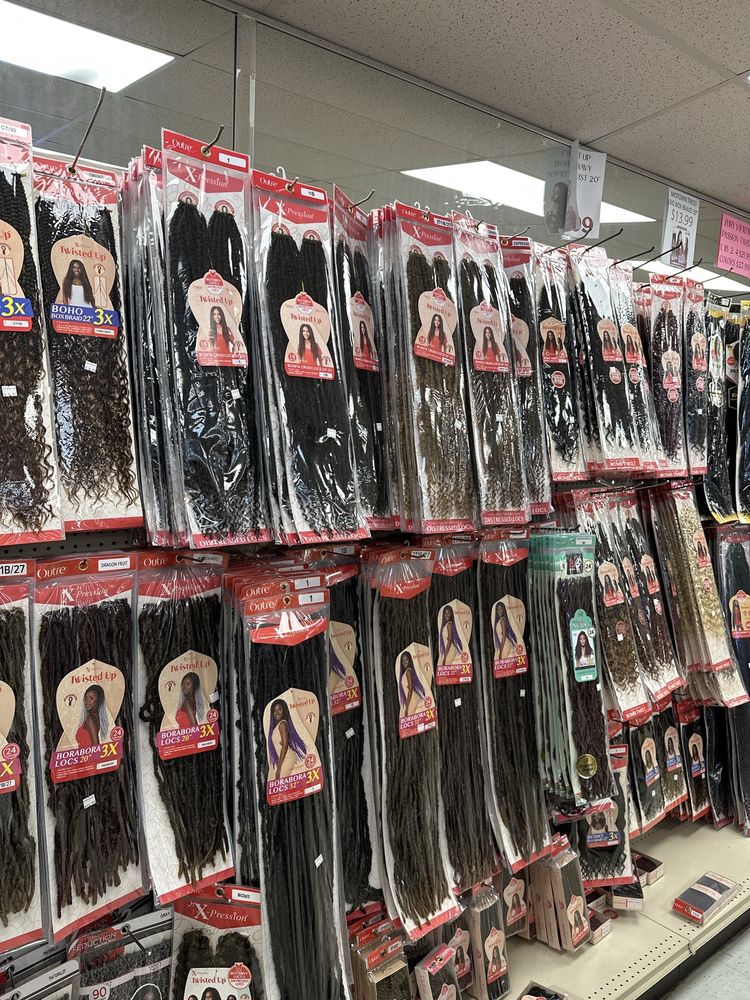 Packs of braiding hair and locs hanging on our pegboard