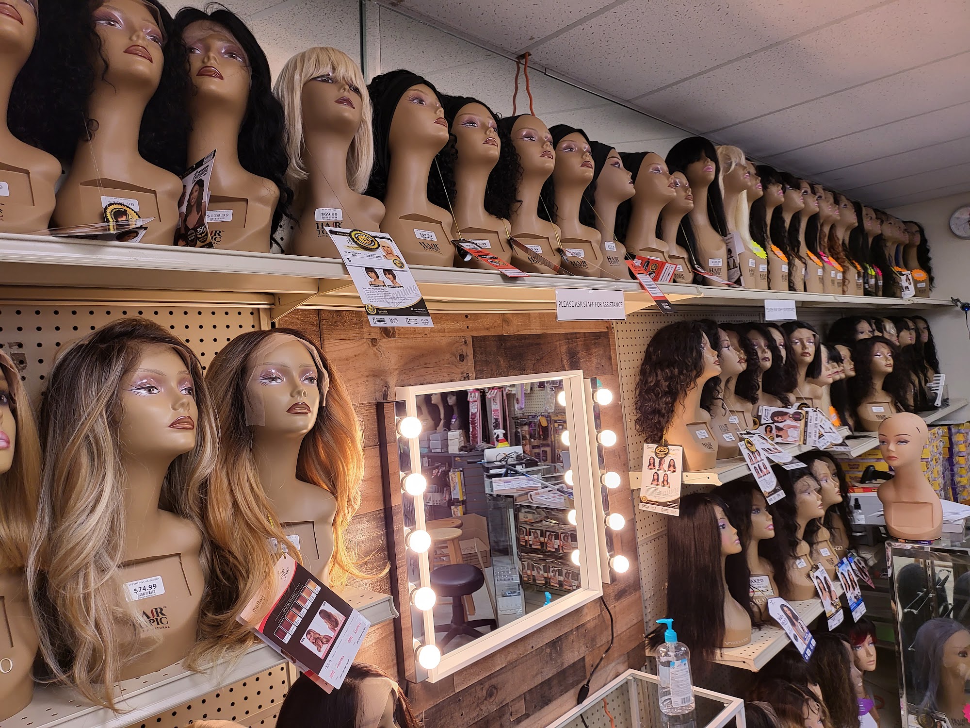 Wigs on our mannequin heads beside the lighted vanity mirror