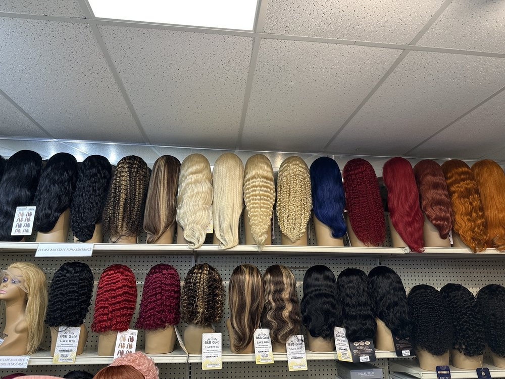A shelf of wigs in black, blonde, copper, and color on our wall