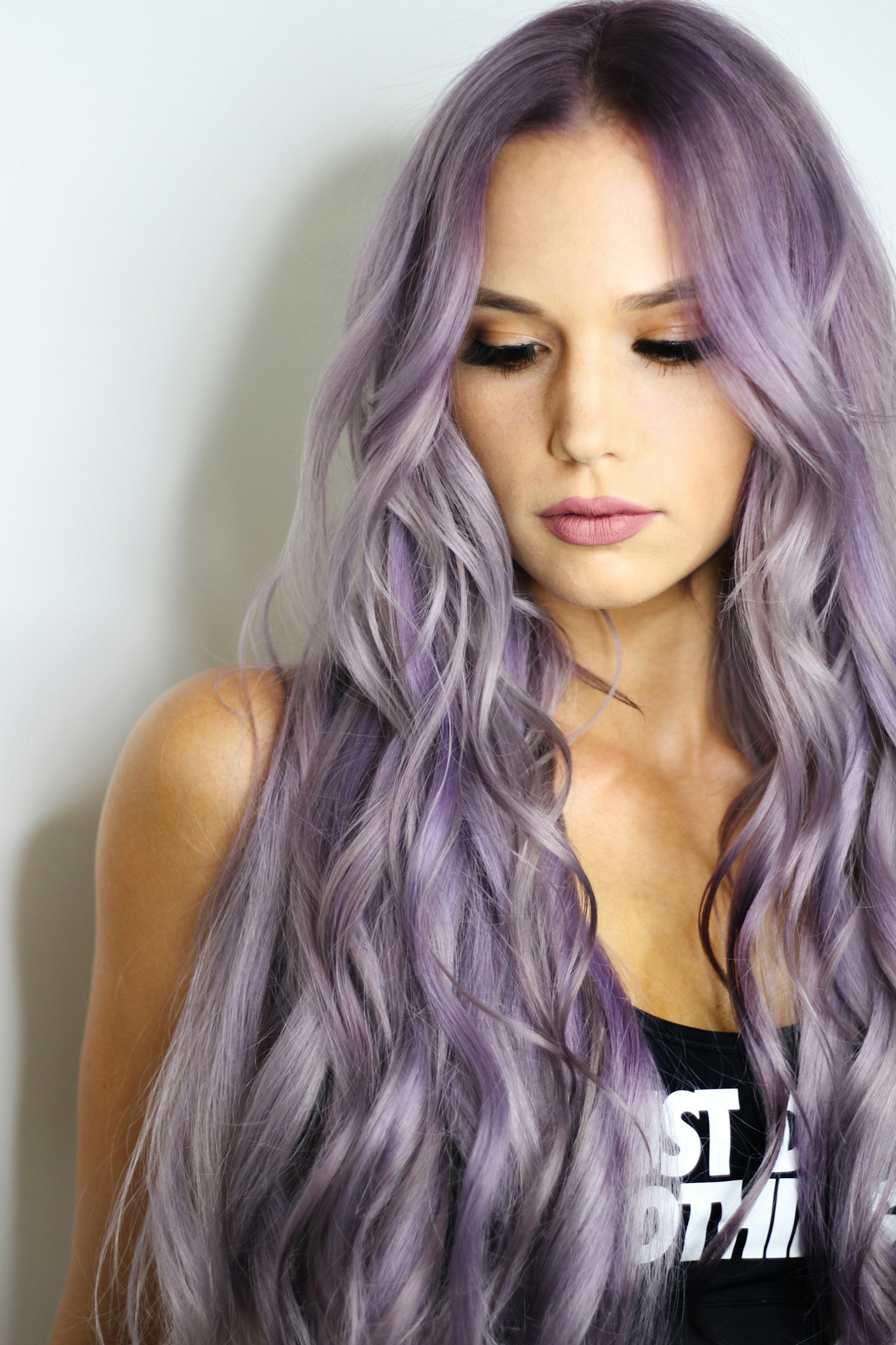 Long lavender waves and a finished makeup look, photographed in studio light.