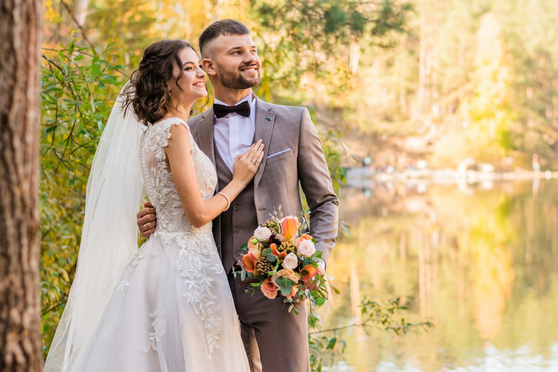 A bride in a lace gown with a soft half-updo and veil