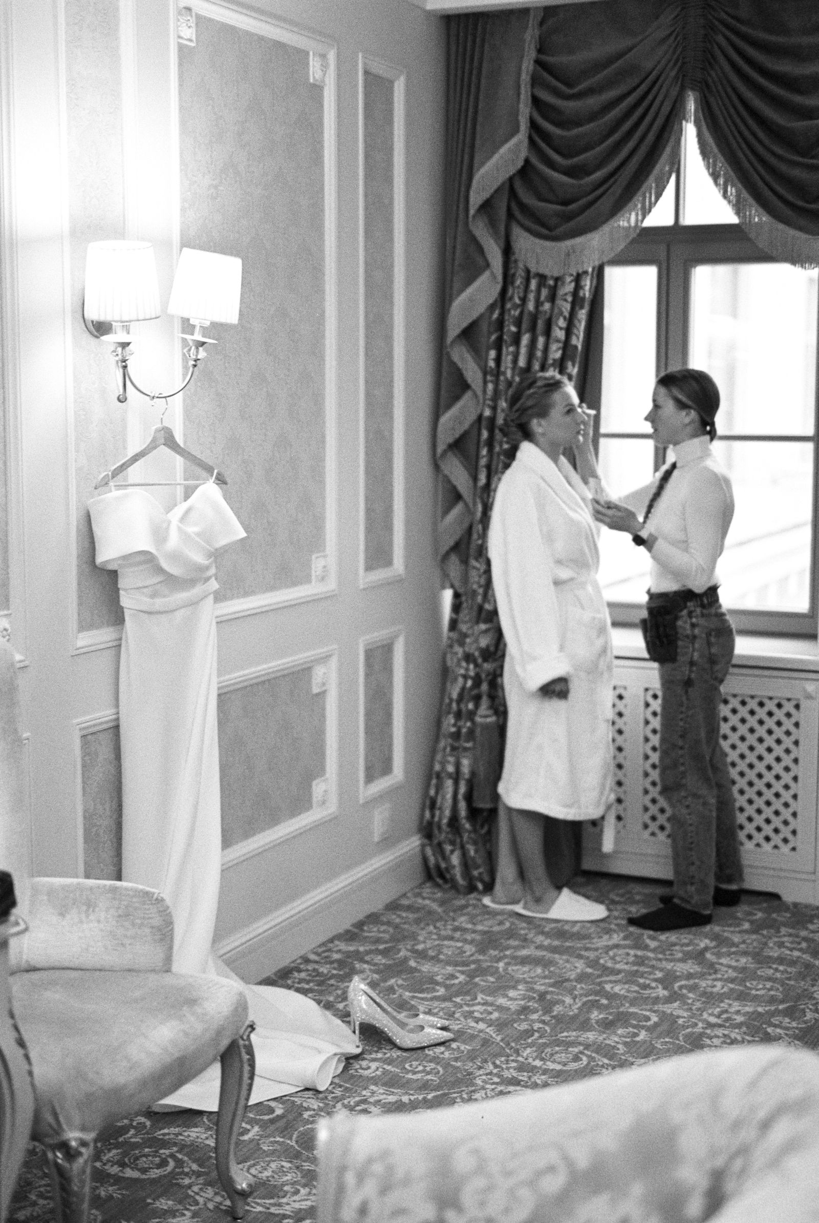 A bride in a robe by the window while we work on her makeup