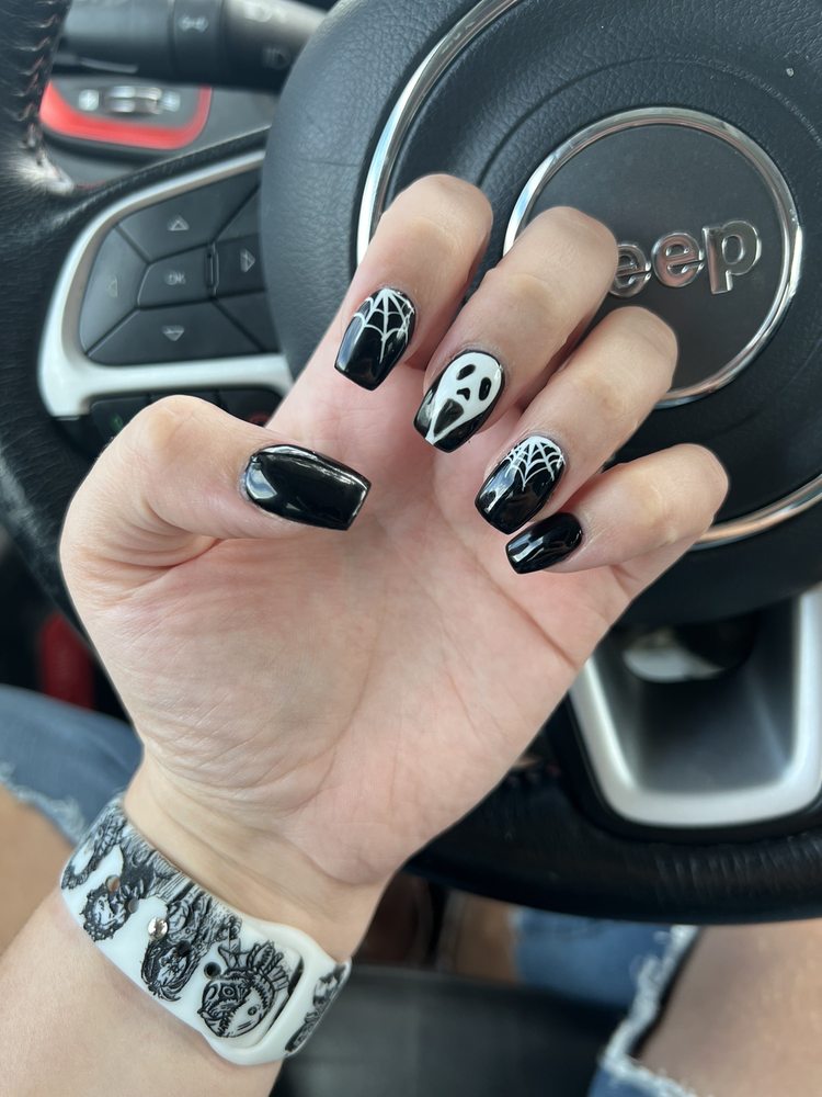 Black coffin nails with white Halloween art, a spiderweb and Ghostface.