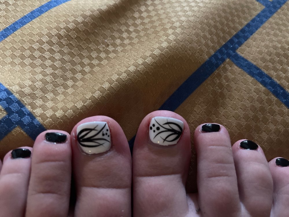 Black pedicure with white leaf art on the big toes.