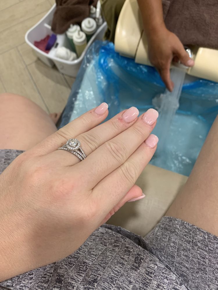 A blush manicure over our pedicure basin as it fills, a brown towel on the cream chair.