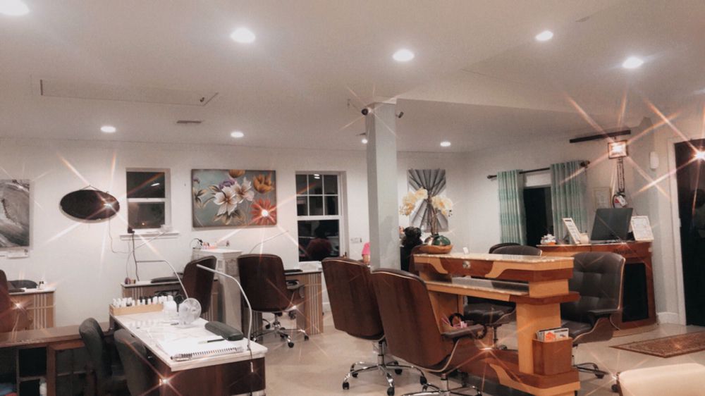 Our manicure row: wood desks, leather chairs, and the floral wall under the shop lights.