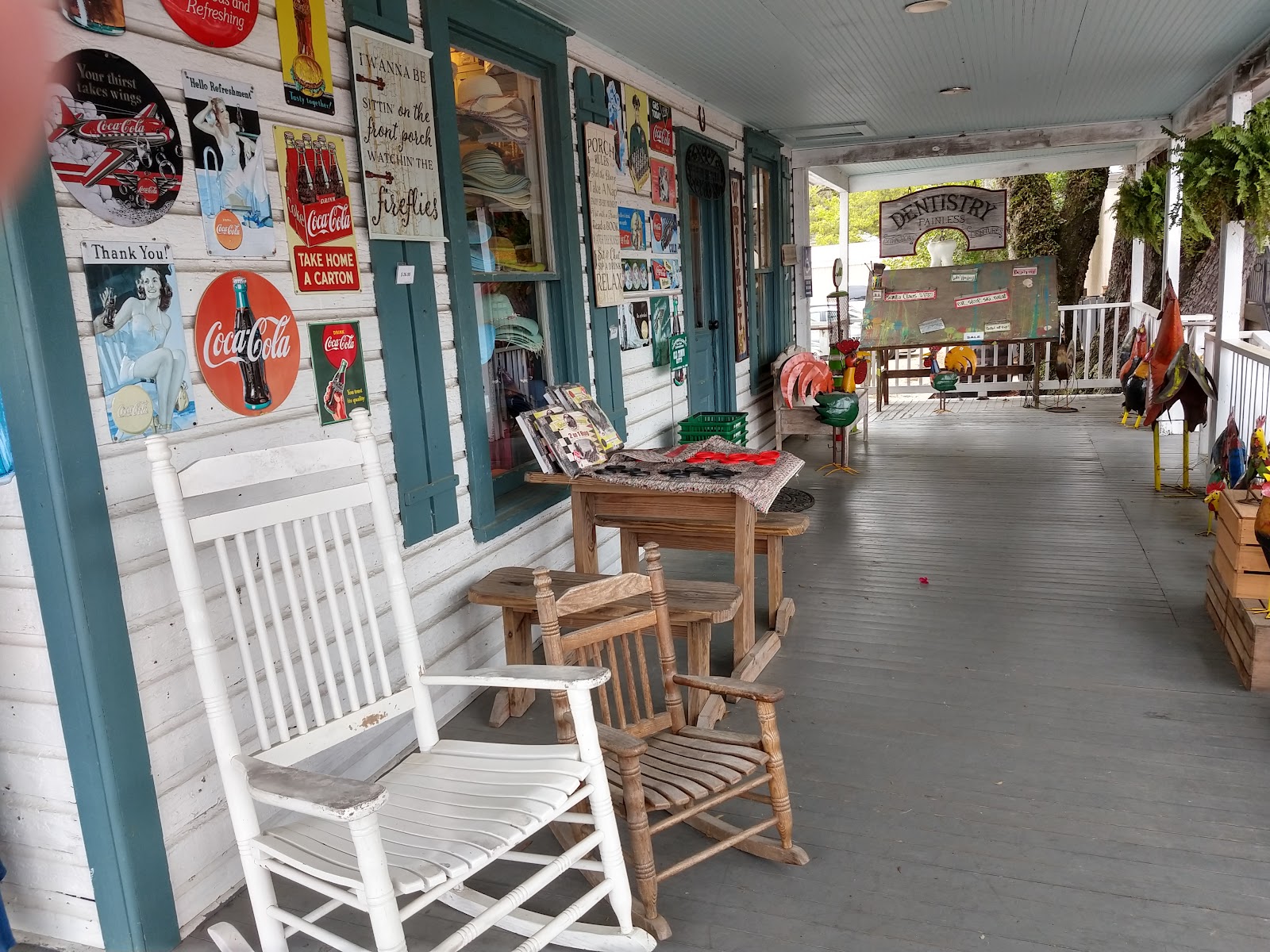 Our white porch from the mulch: Welcome arrow, oval shop signs, racks of clothes