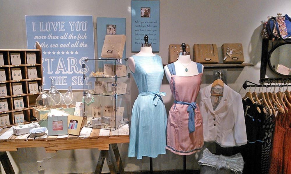 Sky-blue and dusty-rose dresses on forms beside jewelry cubbies