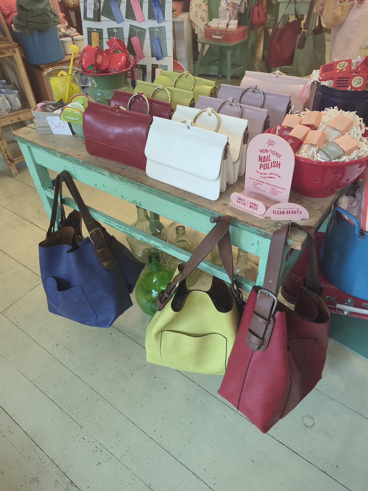 Mint-green table stacked with ring-handle handbags and totes