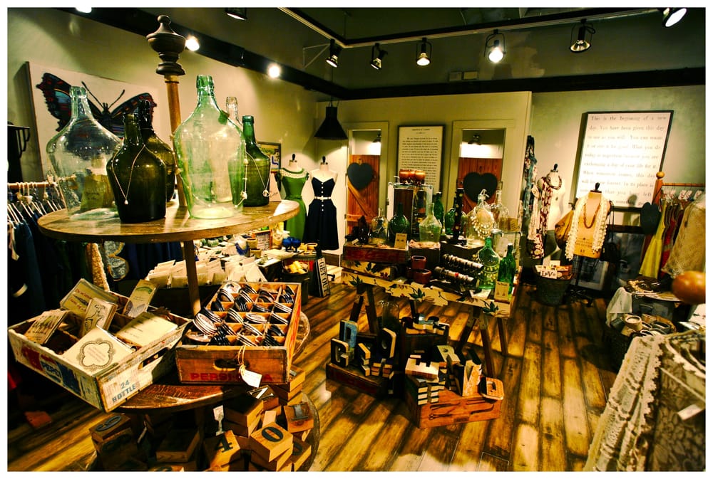 Our shop floor with dresses on forms, green glass bottles, and wooden crates