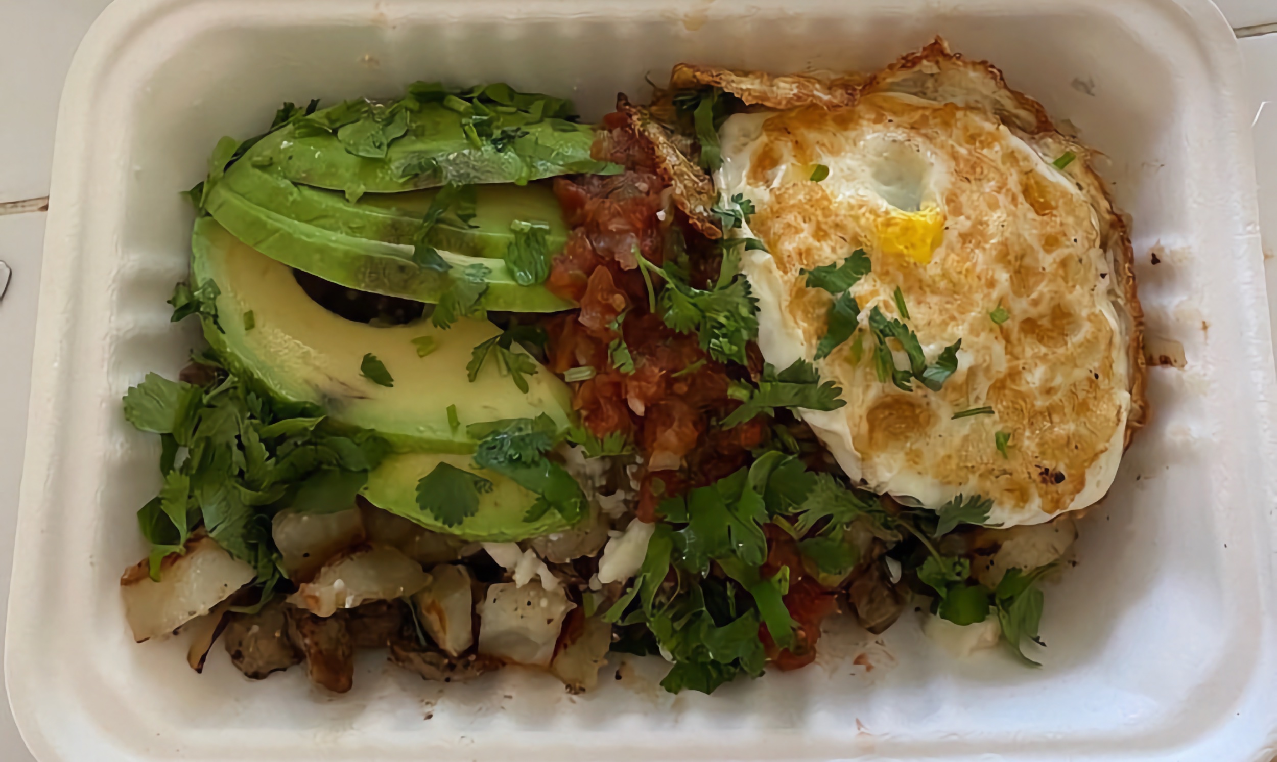 A to-go box of our carne asada hash