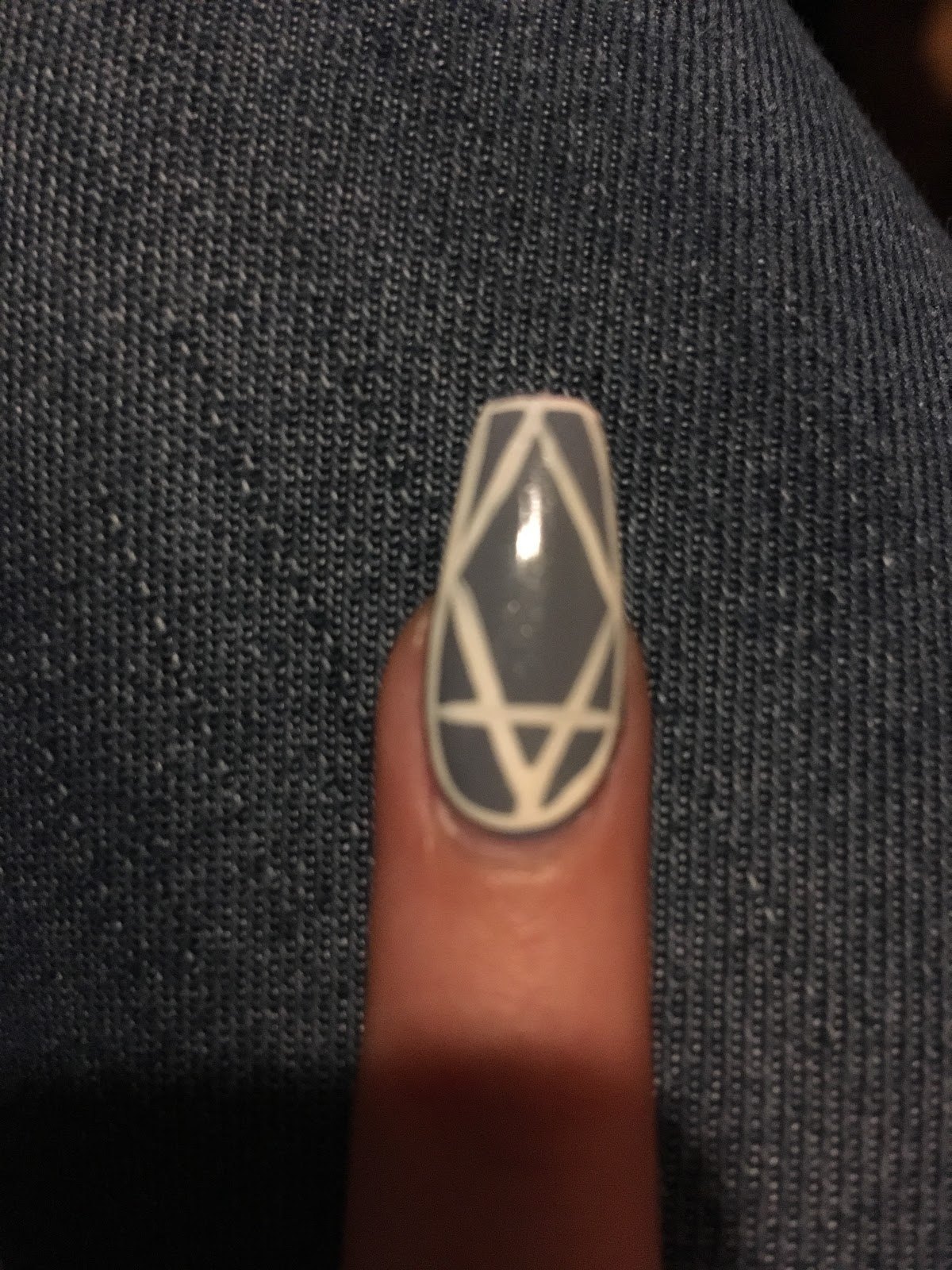Charcoal coffin nail with white geometric line work.