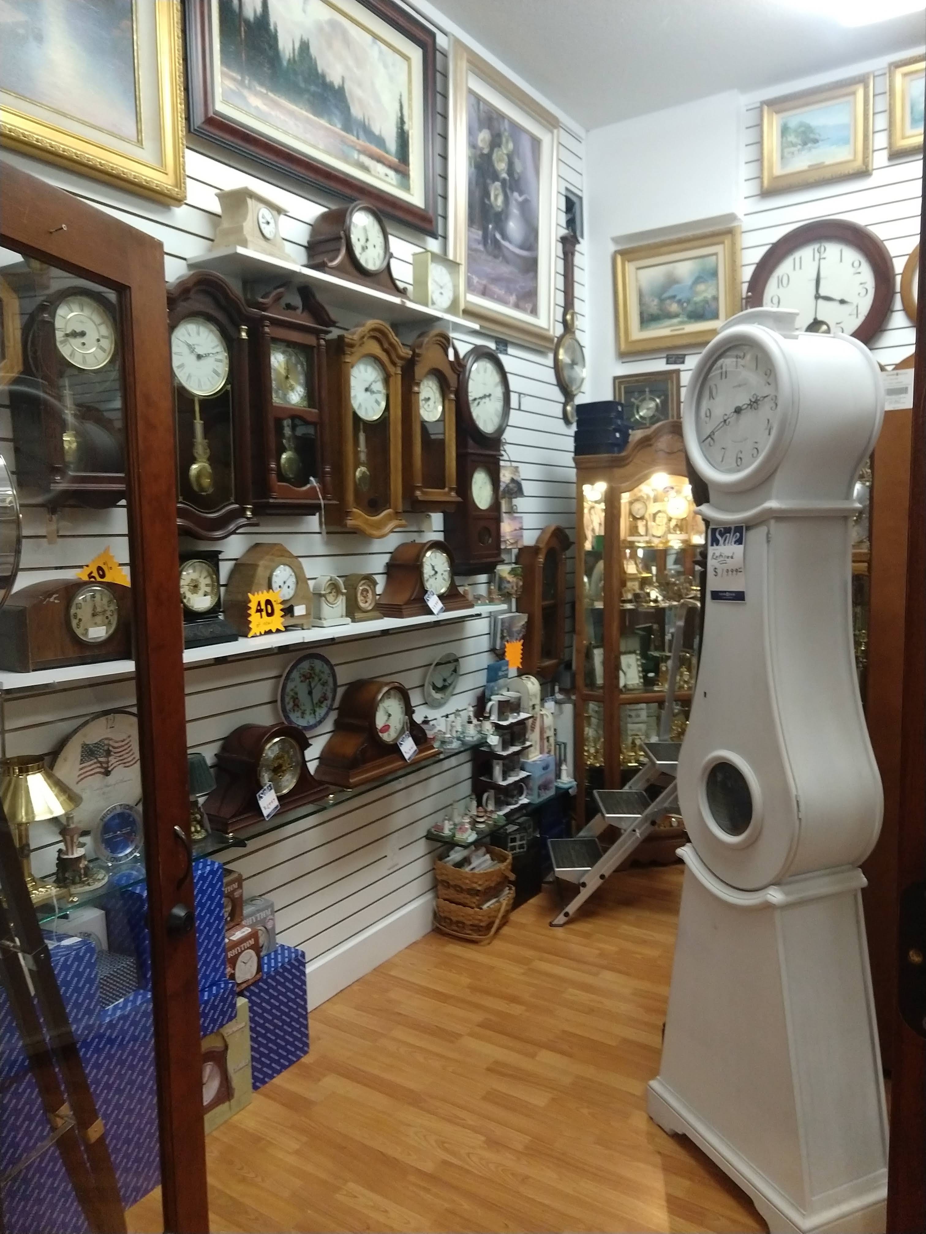 Wall and mantel clocks on the slatwall, with a white Mora-style tall clock.
