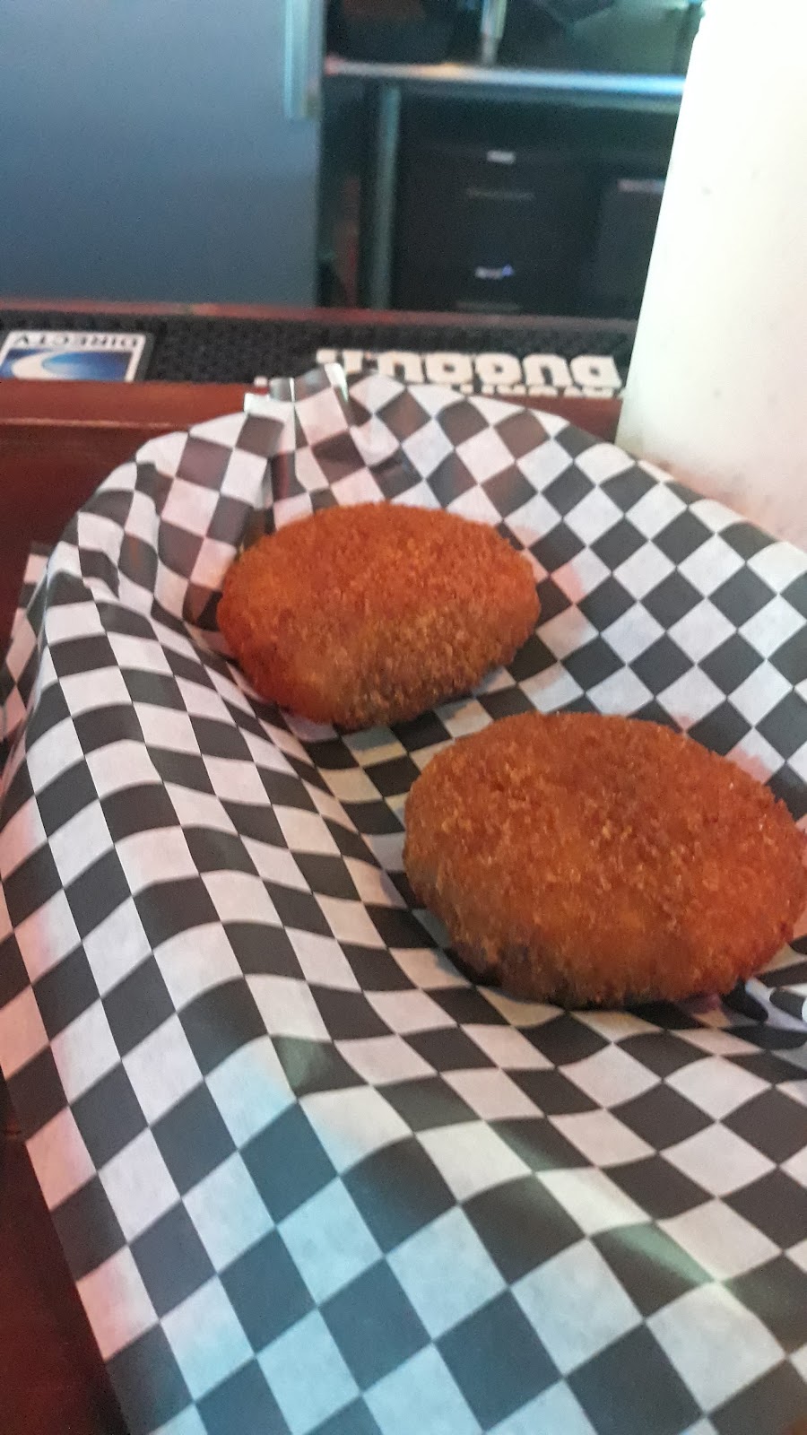 Two fried baskets on checkered paper at the bar.