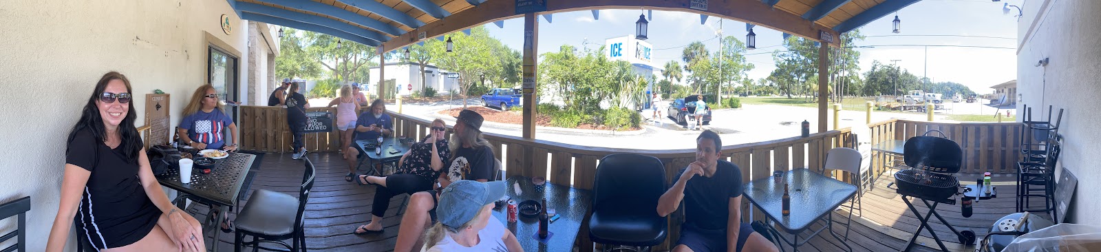 Our patio in daylight, wood deck, blue beams, and tables on the lot side.