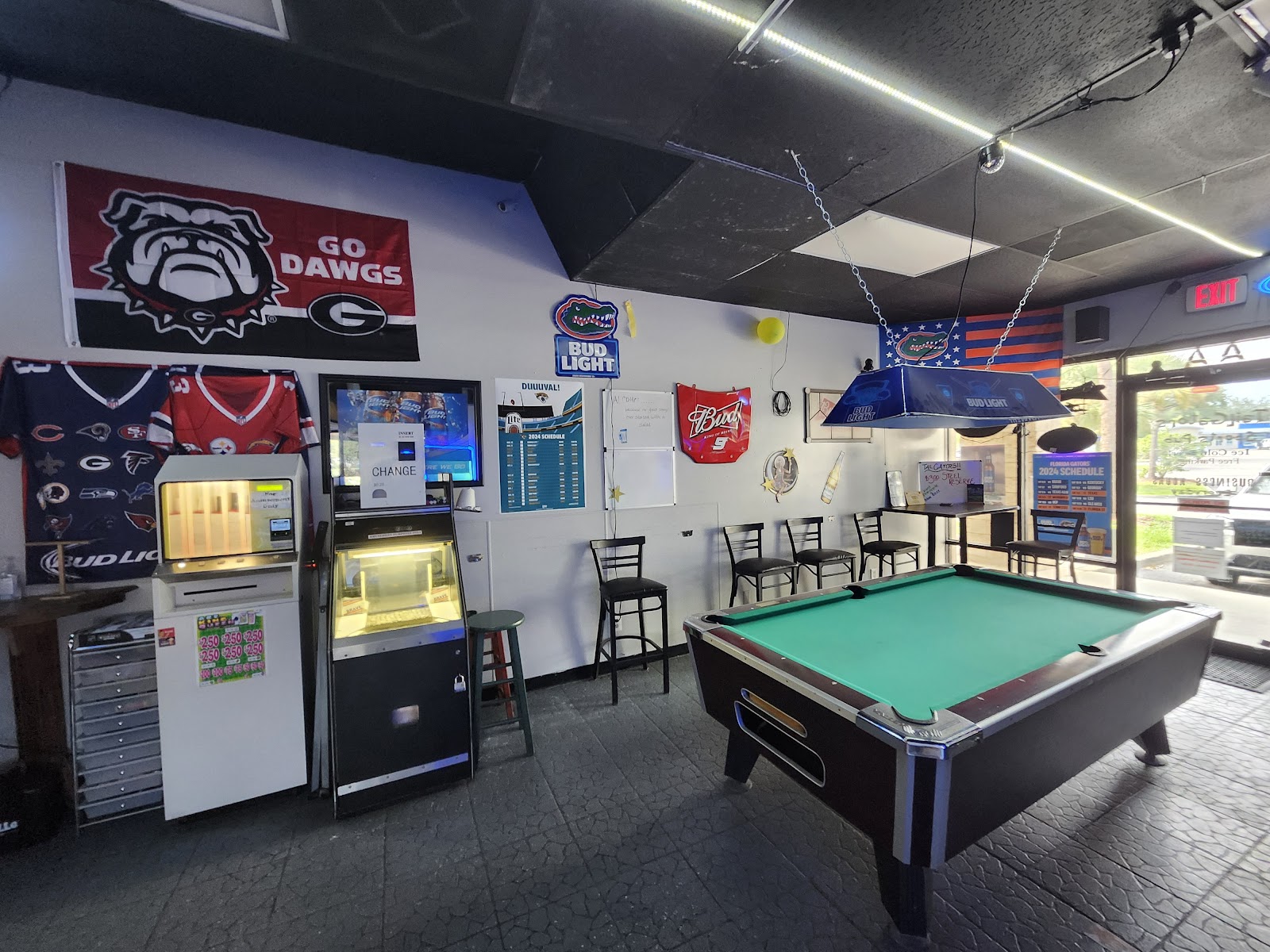 Our pool table under the Bud Light lamp, with Gators and Dawgs gear on the walls.