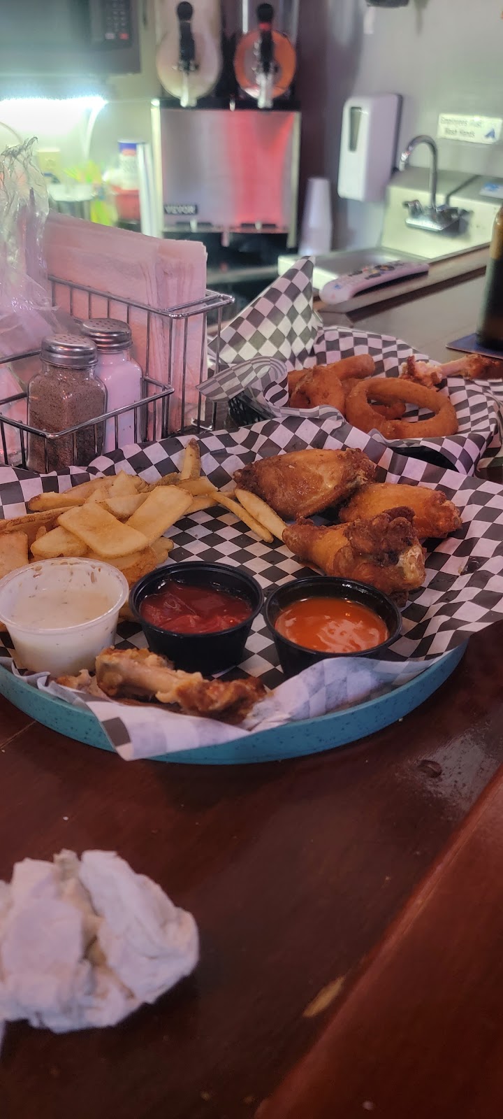 Wings, fries, and onion rings in checkered baskets on our bar.