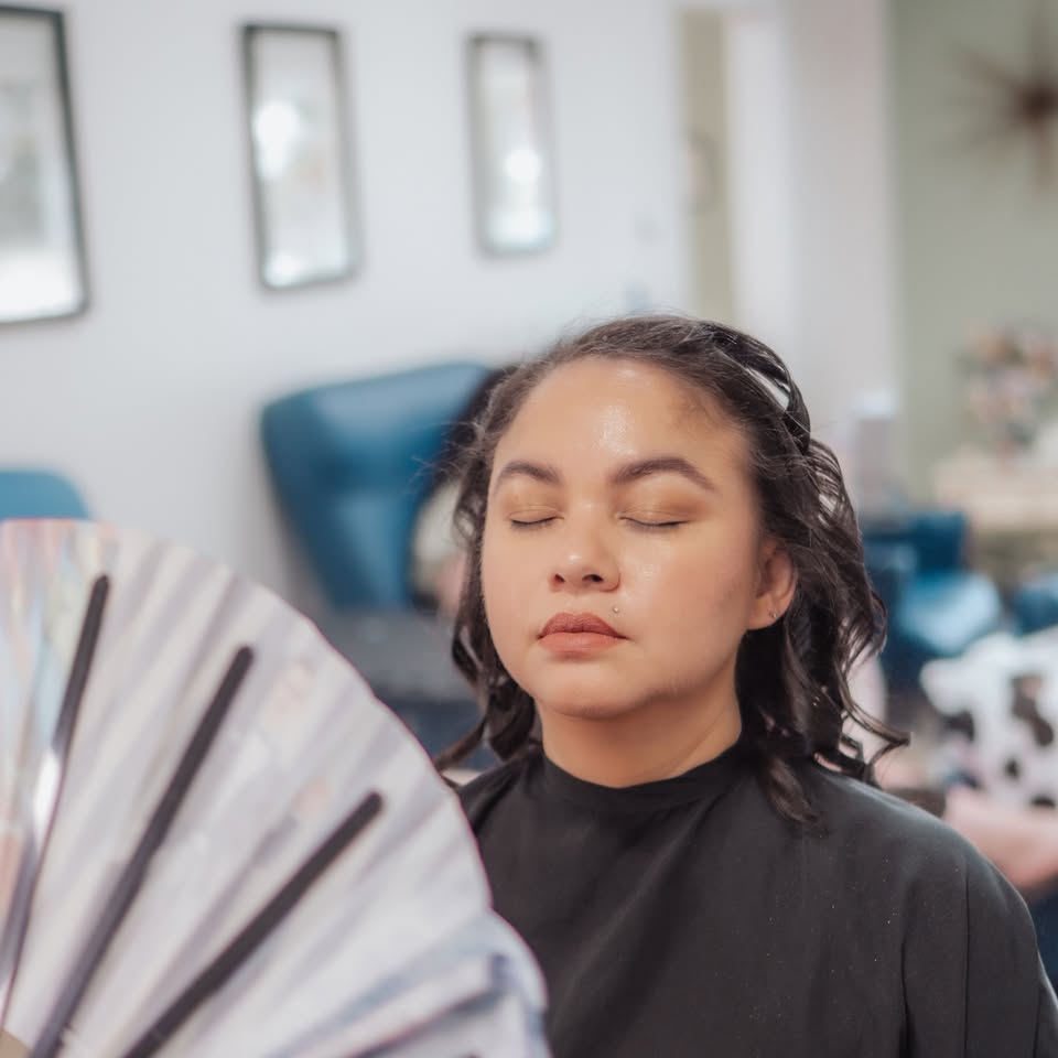 A guest in a salon cape, eyes closed, after chair time.