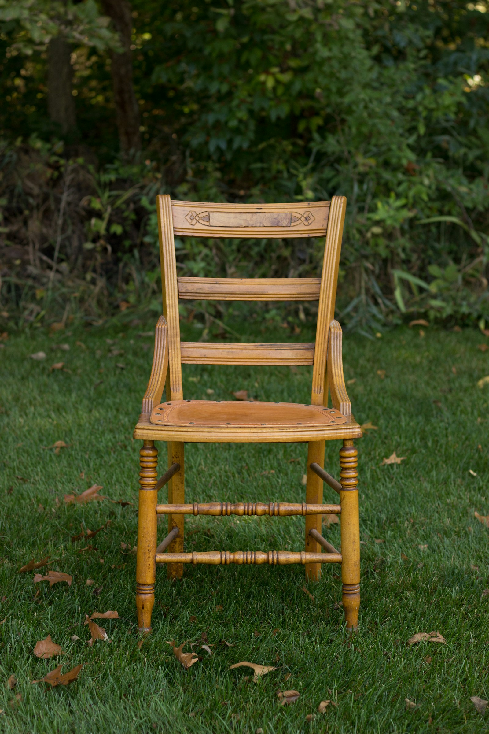 A carved wooden chair standing on grass.