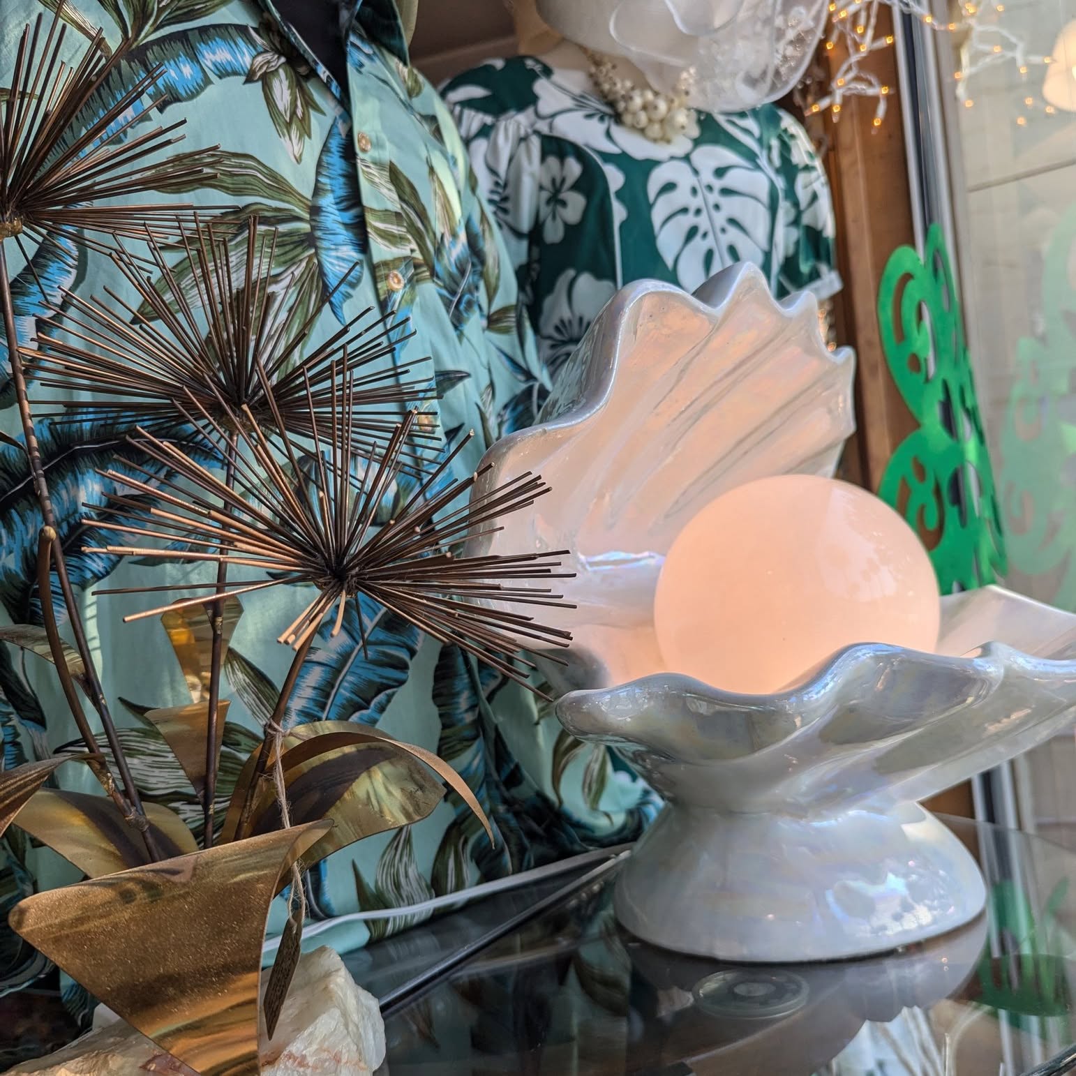 Clam-shell lamp, brass palm, and tropical print in the house.