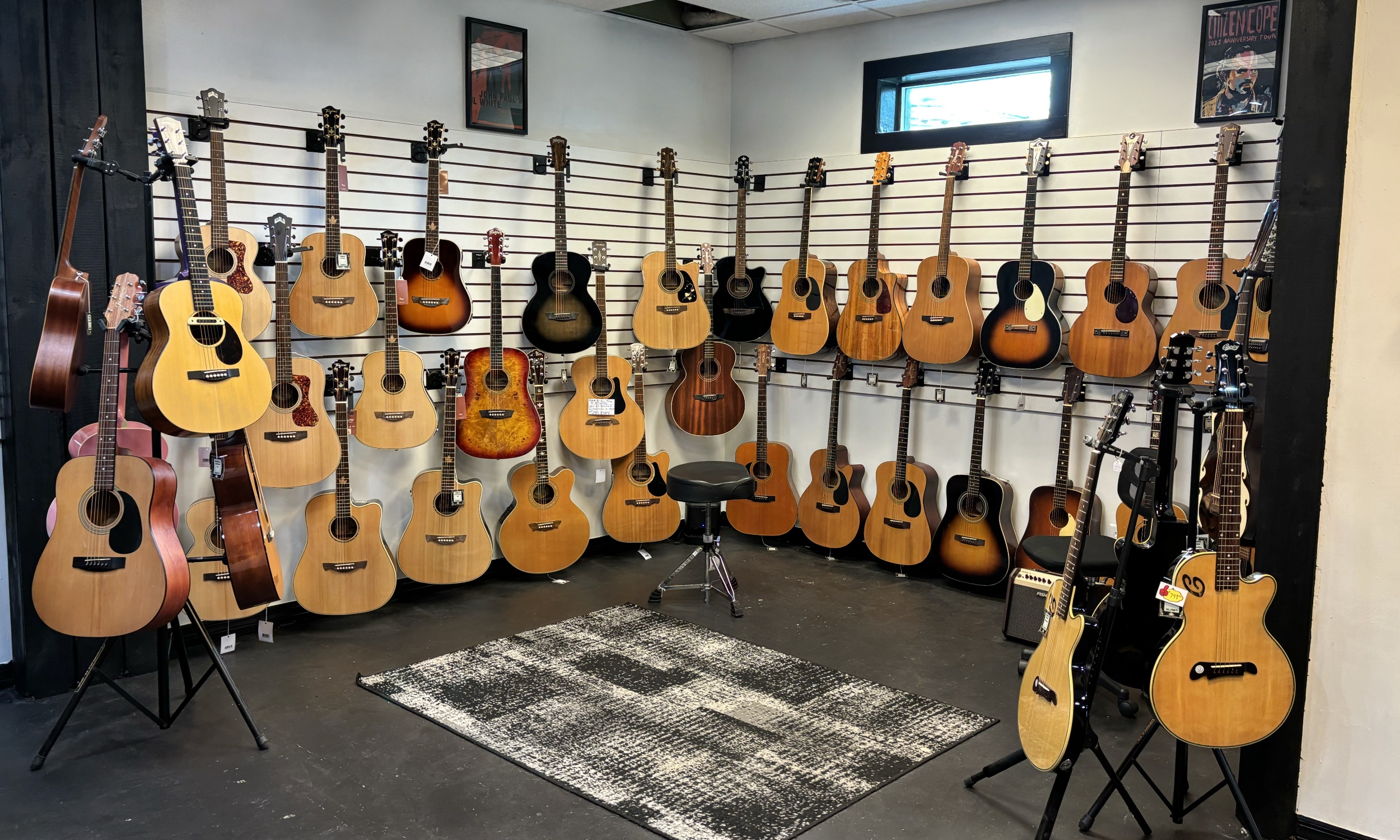 Acoustic guitars hanging on our wall, a stool, and an amp on the floor.