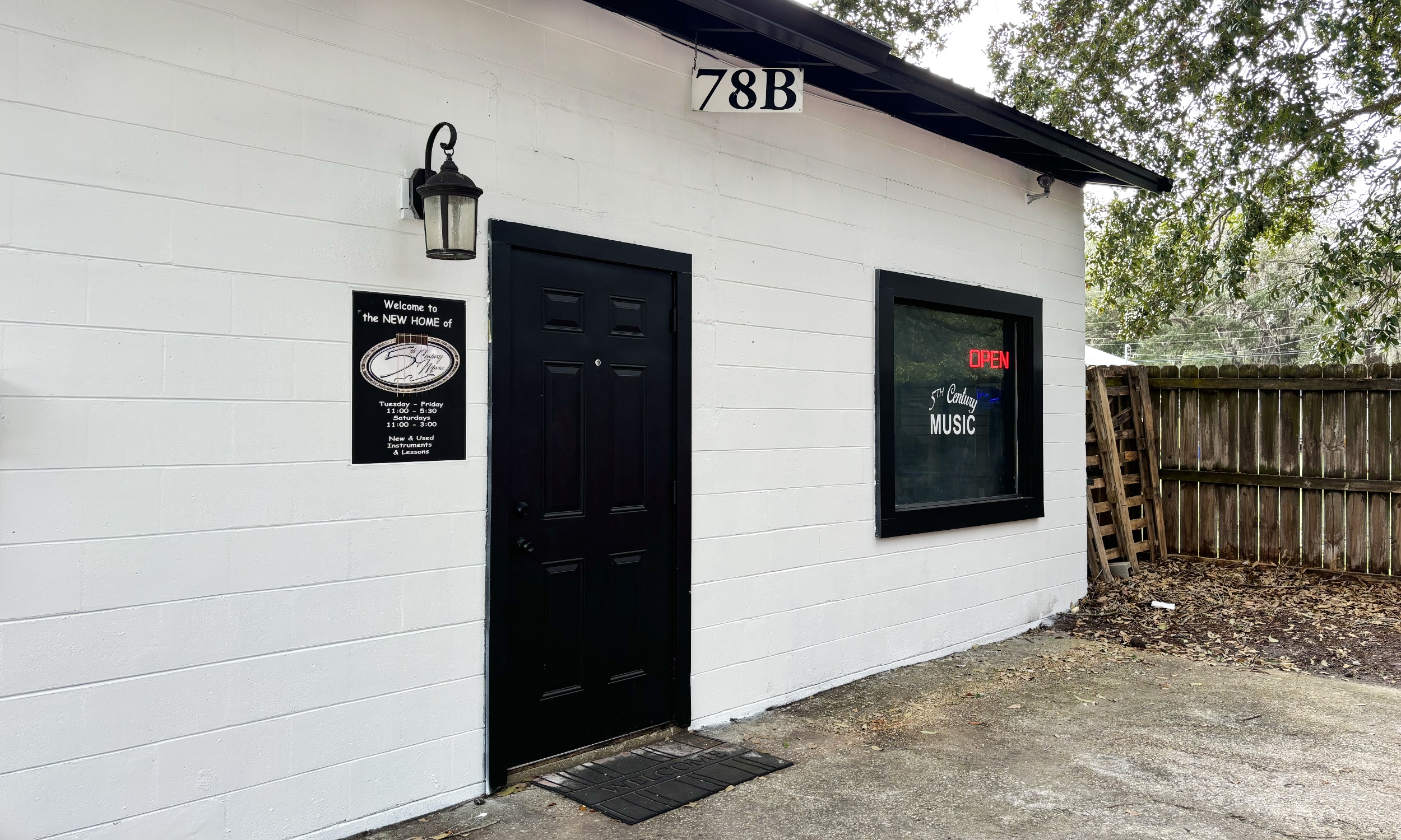Our shop front at 78B, white block wall, black door, and window lettering.