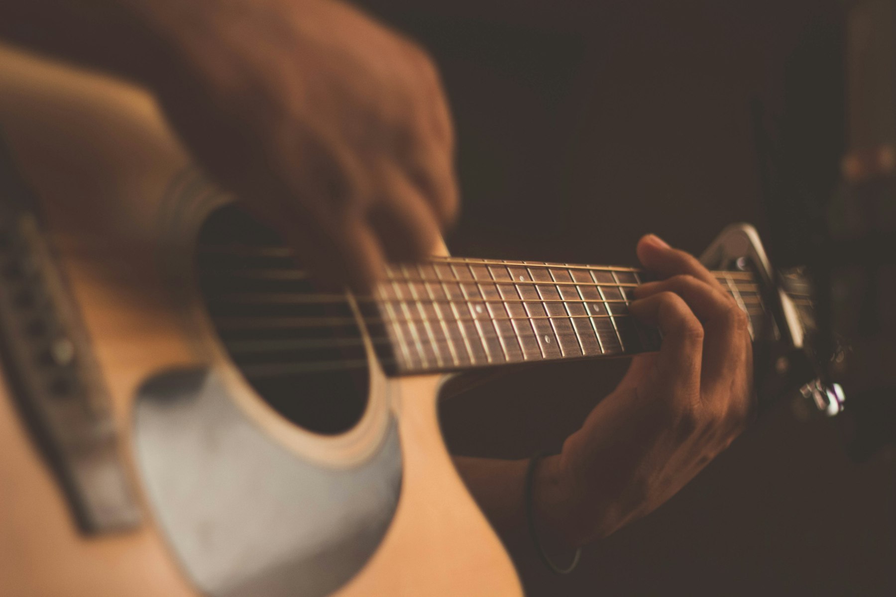 Hands on an acoustic, capo on the neck.