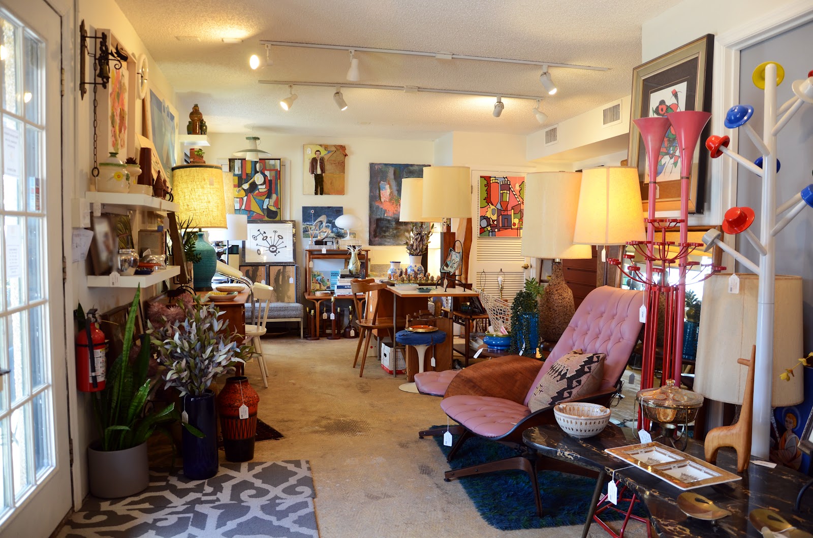 Looking down our floor: pink lounge, lamps, ceramics, and paintings on the wall.