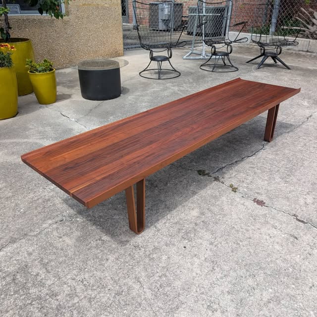 Teak bench outside with yellow planters.