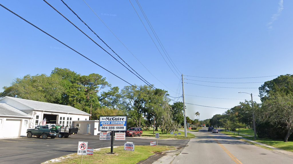 Close view of the Ken McGuire Auto Service sign and open bay.