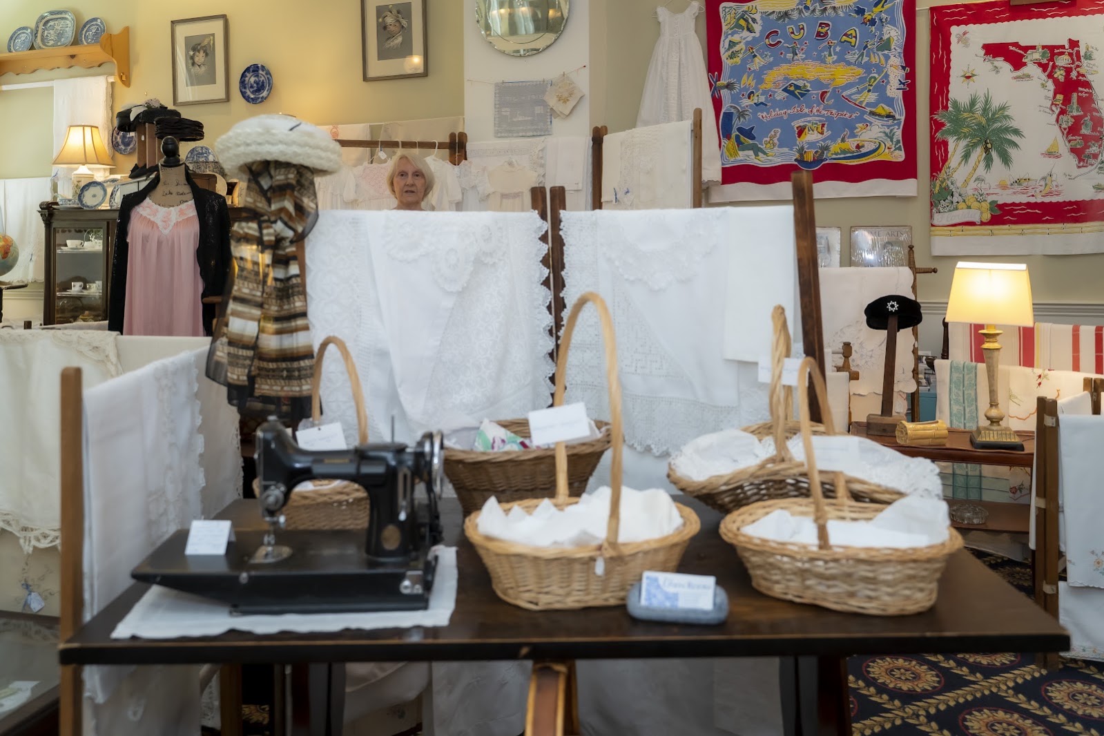 The Singer on our table, wicker baskets of linens, and cloth hanging through the room.