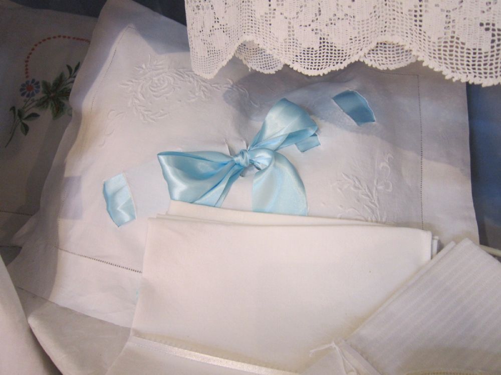 A white pillow sham with a light blue satin ribbon and lace above it.