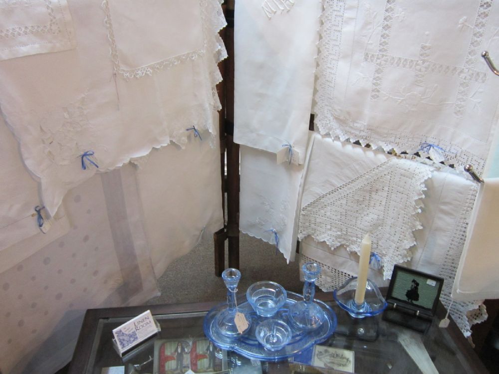 Hanging white linens behind blue pressed glass and our table cards.
