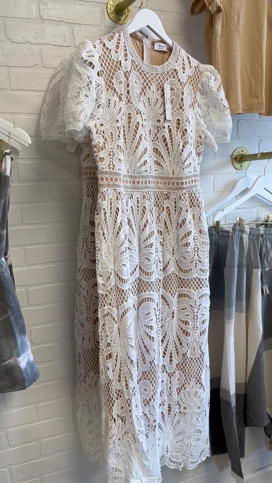 White lace dress on our gold rail against white brick.