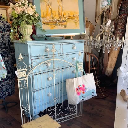 A sky-blue painted dresser with porcelain knobs and a white iron gate.