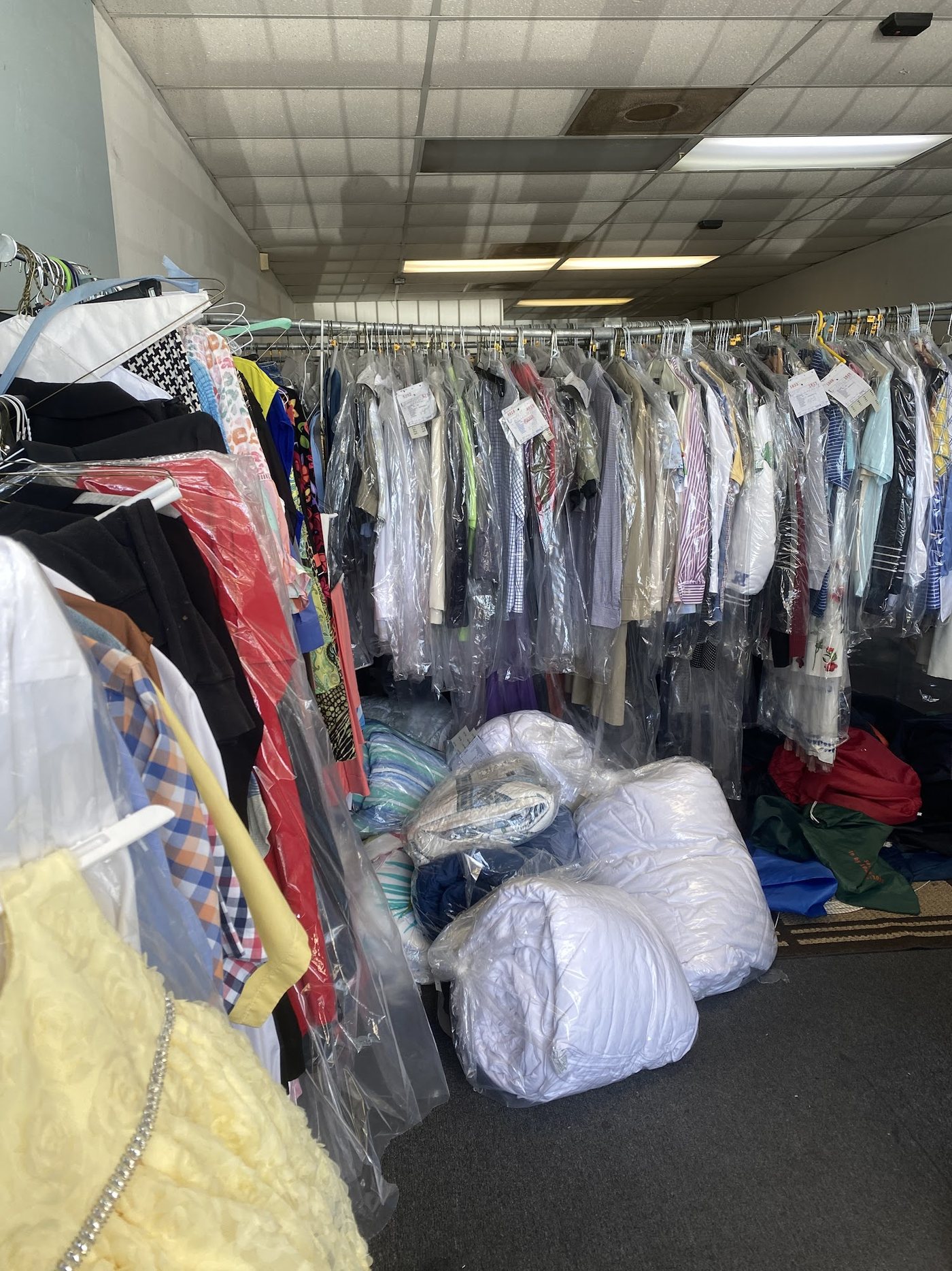 Clothes on our rail in plastic bags, paper tags on the hangers